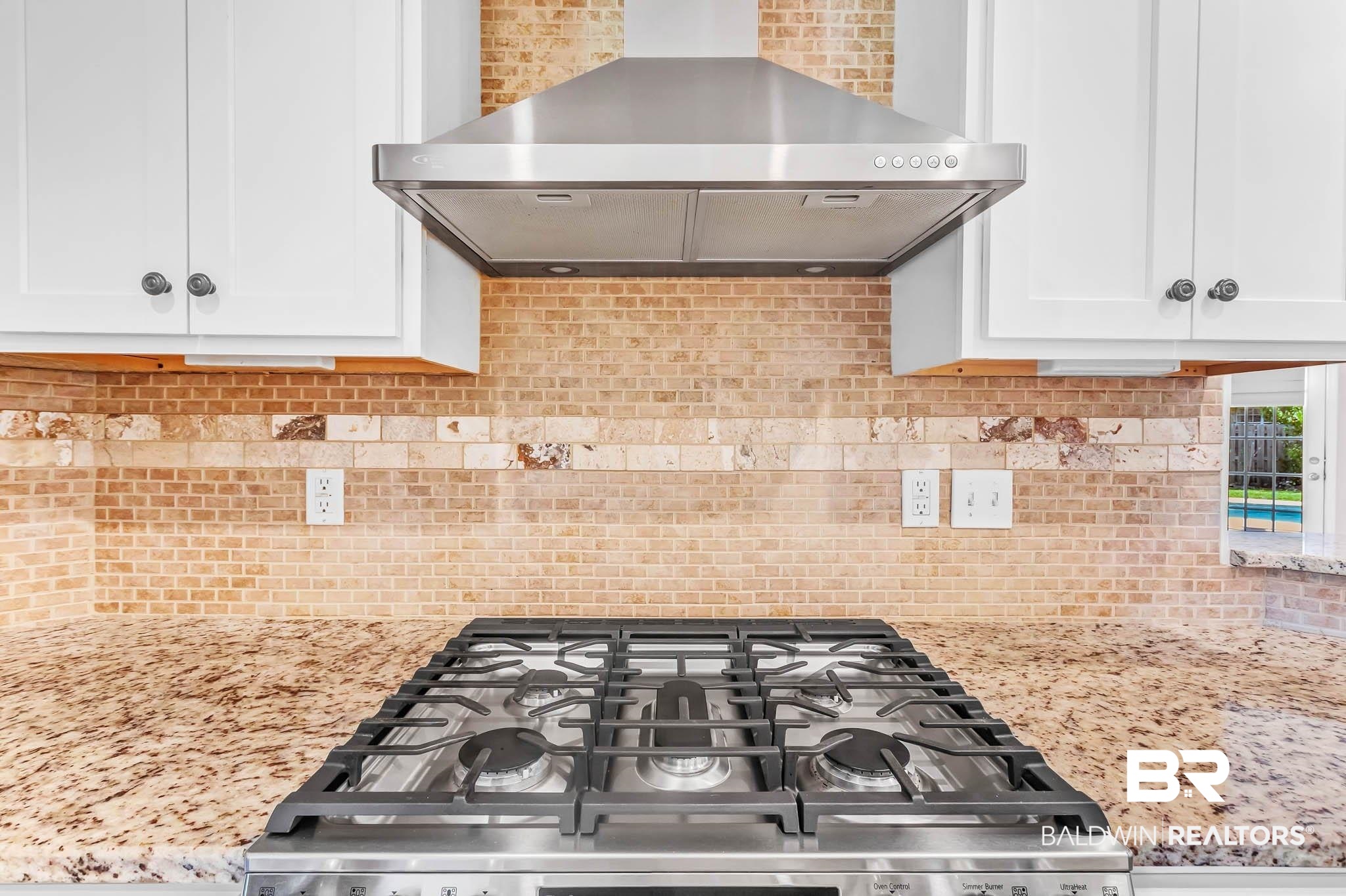 9607 Czar Court Fairhope, AL 36532 - Photo 14 of 42 Kitchen with wall chimney exhaust hood, white cabinets, stove, light stone counters, and backsplash