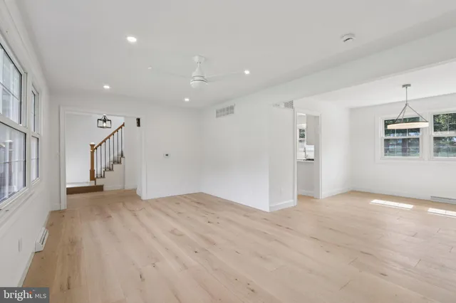 a view of an empty room with wooden floor and windows