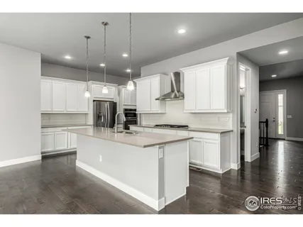a large white kitchen with lots of counter space a sink appliances and cabinets
