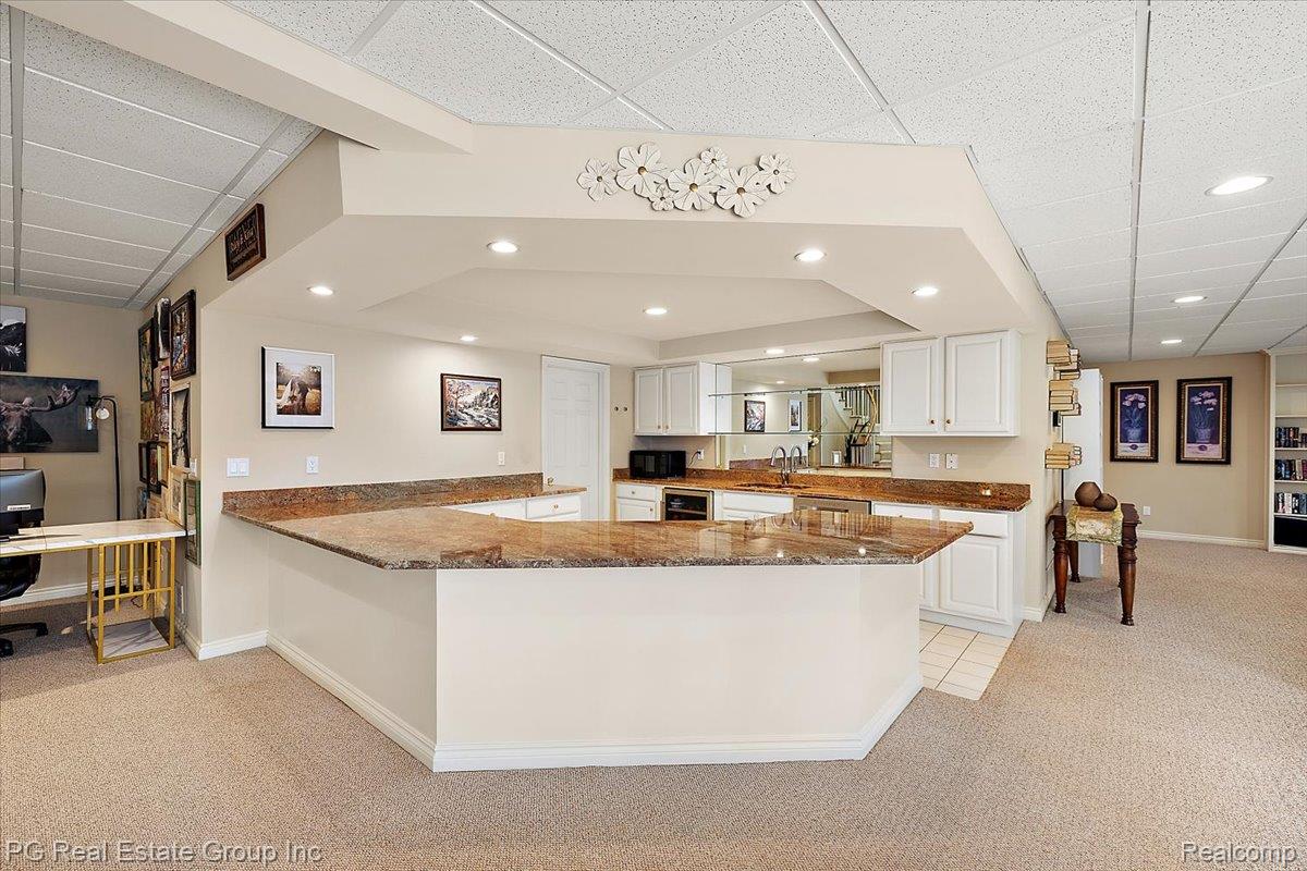 3571 Cedar Brook Drive Rochester, MI 48309 - Photo 49 of 57 Kitchen featuring light colored carpet, a drop ceiling, dark stone countertops, white cabinets, and a peninsula