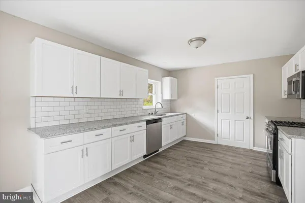 a kitchen with granite countertop white cabinets and white appliances