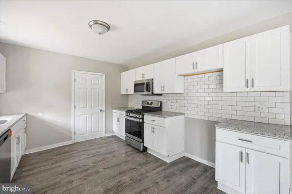 a kitchen with granite countertop white cabinets and stainless steel appliances