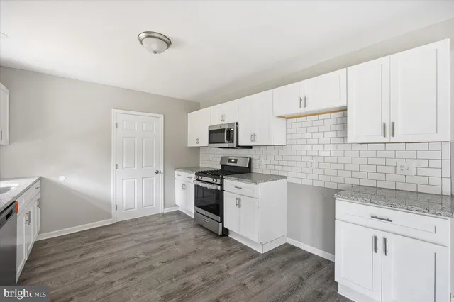 a kitchen with granite countertop white cabinets and stainless steel appliances