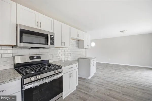 a kitchen with granite countertop a stove and a microwave