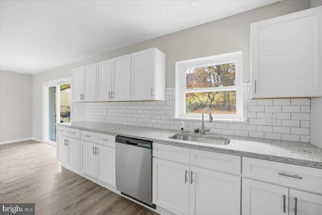 a kitchen with stainless steel appliances granite countertop white cabinets sink and window