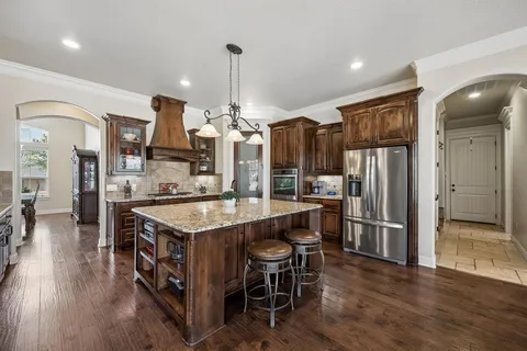 a kitchen with stainless steel appliances granite countertop a sink a stove and a wooden cabinets