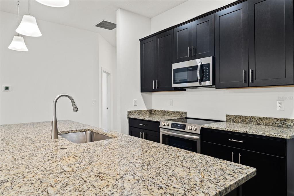 15171 Pomp Parkway Weeki Wachee, FL 34614 - Photo 18 of 50 a kitchen with stainless steel appliances kitchen island granite countertop a stove a sink and a microwave