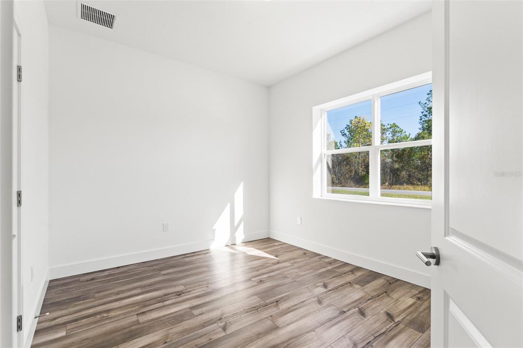 15171 Pomp Parkway Weeki Wachee, FL 34614 - Photo 7 of 50 a view of an empty room with wooden floor and a window