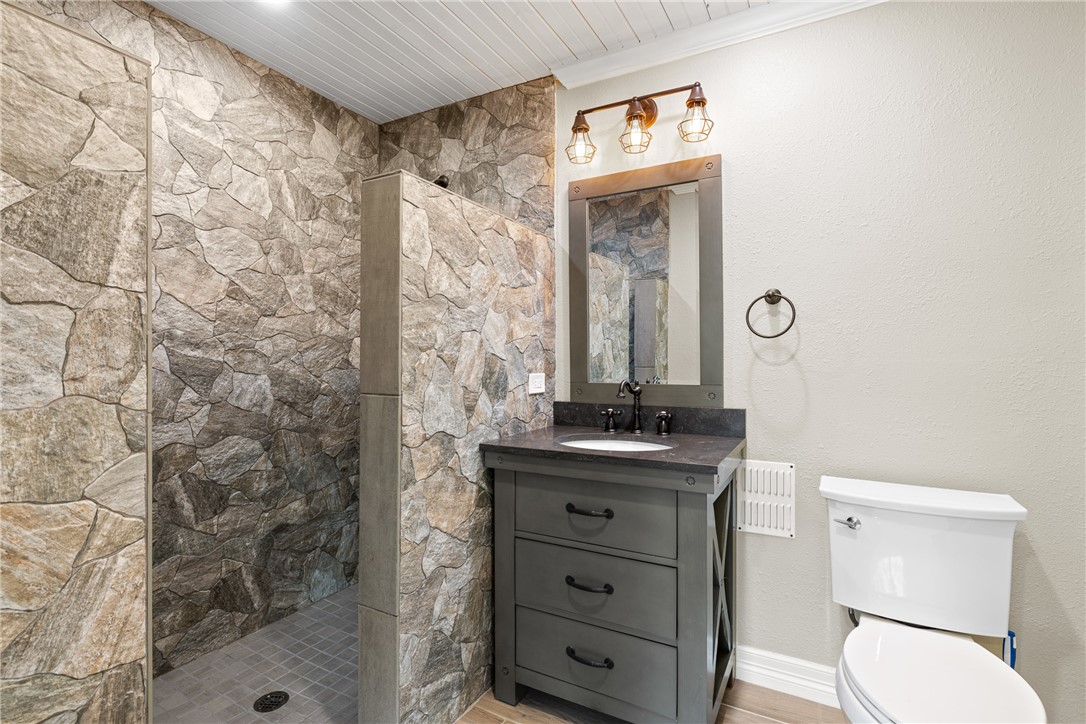9249 Clyde Acord Road Franklin, TX 77856 - Photo 11 of 23 Bathroom with a tile shower, toilet, vanity, and wood finished floors