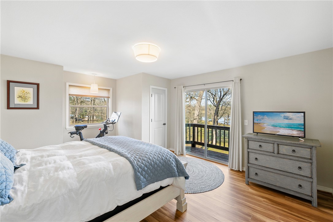 9249 Clyde Acord Road Franklin, TX 77856 - Photo 13 of 23 Bedroom featuring wood finished floors, baseboards, multiple windows, and access to exterior