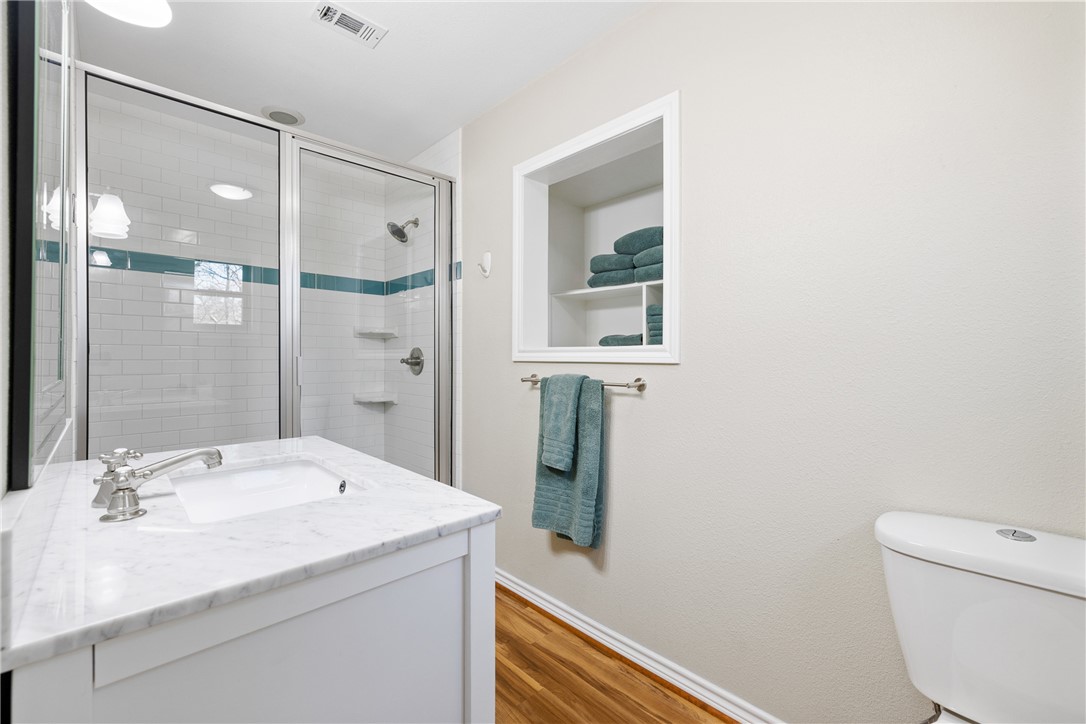 9249 Clyde Acord Road Franklin, TX 77856 - Photo 14 of 23 Full bathroom featuring visible vents, toilet, wood finished floors, a shower stall, and baseboards