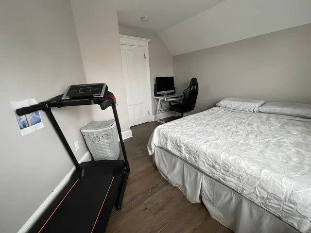 a bedroom with bed chair and mirror