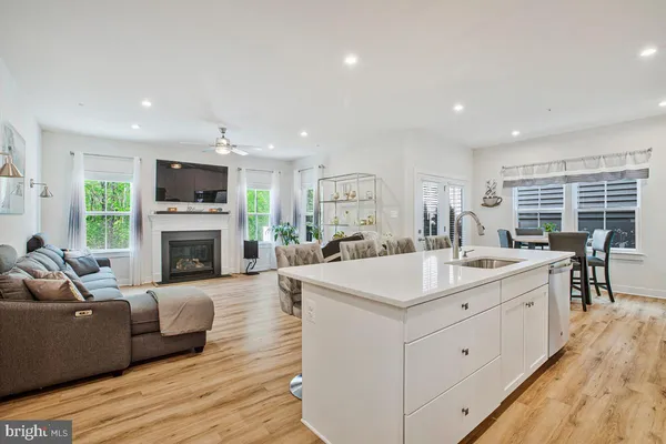 a view of living room kitchen with stainless steel appliances granite countertop living room couch and fireplace