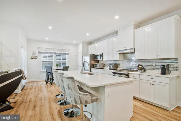 a kitchen with stainless steel appliances a stove a sink a refrigerator white cabinets and wooden floor