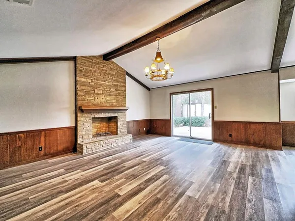 a view of an empty room with wooden floor fireplace and a window