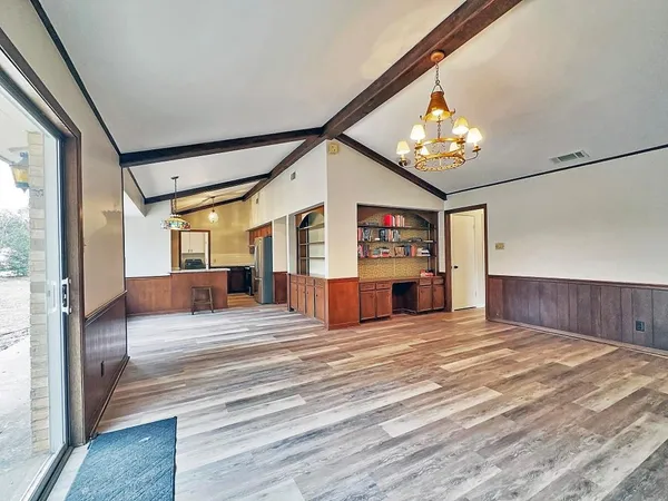 a view of an empty room with furniture and chandelier