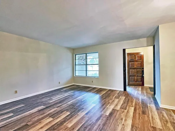 a view of an empty room with wooden floor and a window