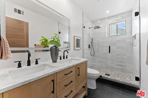 a bathroom with a granite countertop sink a toilet and shower