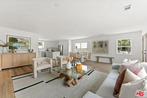 a living room with furniture a rug kitchen view and a window