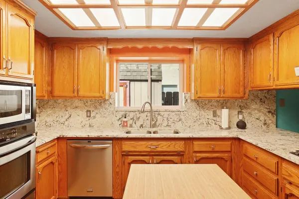 a kitchen with stainless steel appliances granite countertop a sink a stove and a microwave