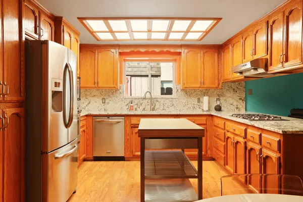 a kitchen with stainless steel appliances granite countertop a refrigerator a sink and dishwasher