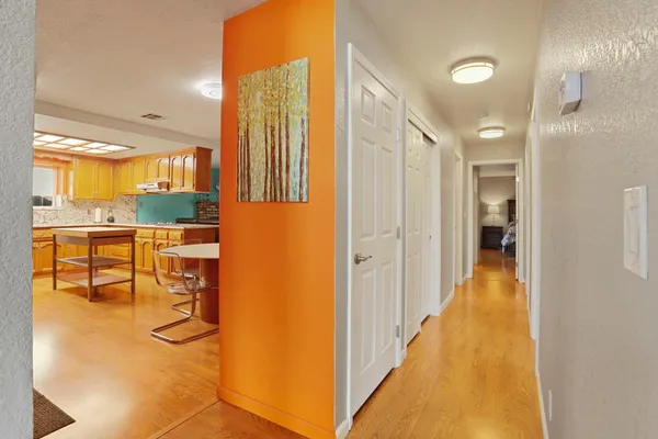 a view of a hallway with wooden floor and a bathroom