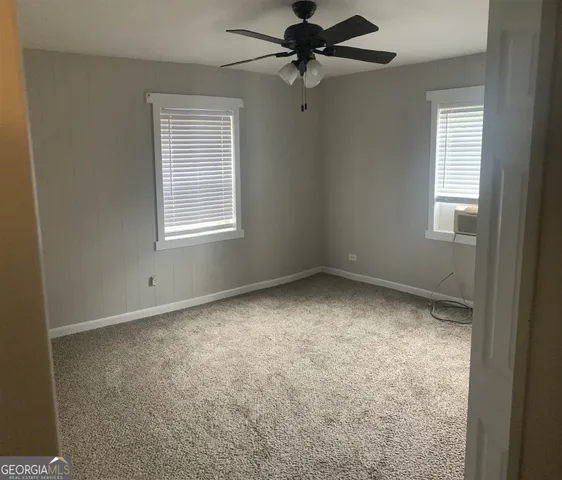 an empty room with a window and a fan