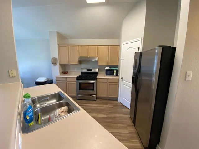 a kitchen with stainless steel appliances granite countertop a refrigerator a stove and a sink