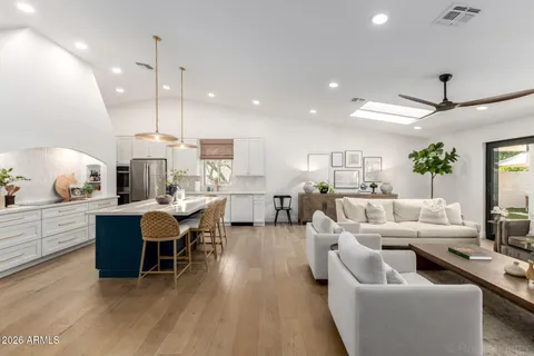 a living room with furniture kitchen view and a wooden floor