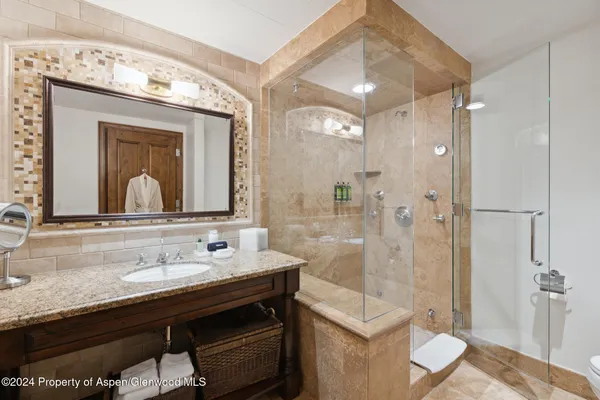 a bathroom with a granite countertop sink mirror and shower