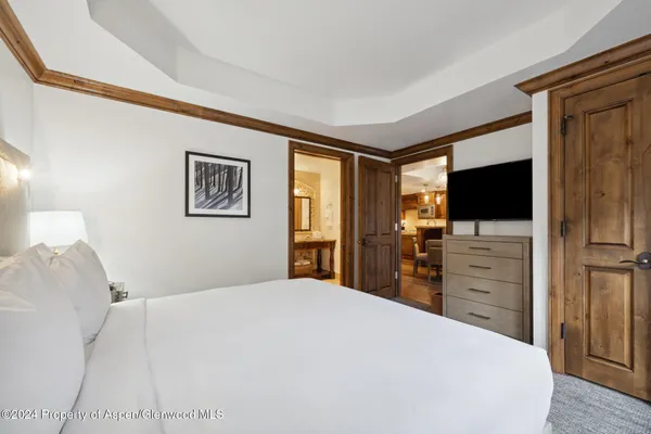 a bedroom with a large bed and a flat tv screen