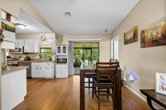 a kitchen with stainless steel appliances granite countertop a stove top oven a sink a dining table and chairs with wooden floor