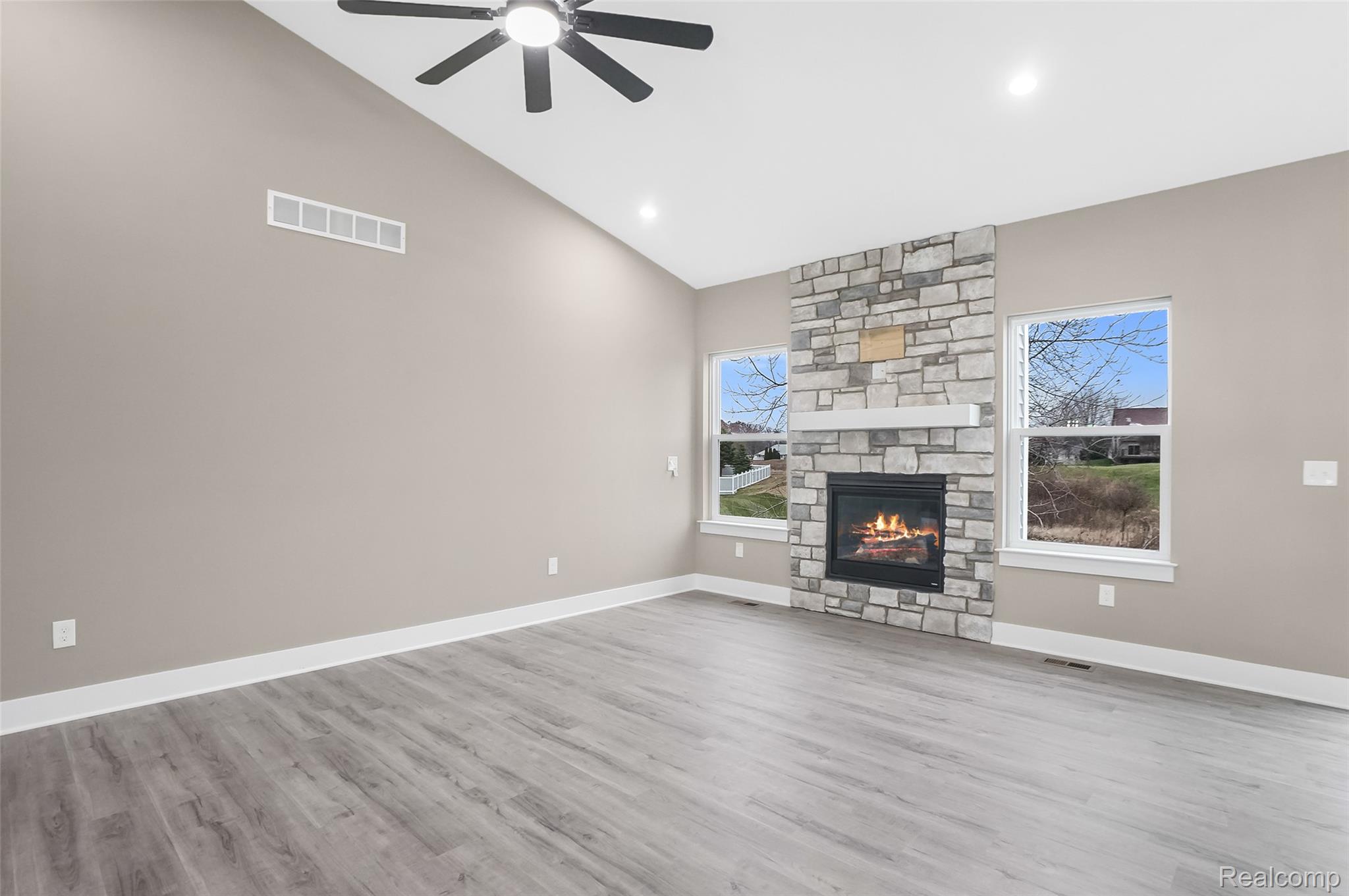 Unfurnished living room featuring a fireplace, vaulted ceiling, light wood finished floors, ceiling fan, and recessed lighting