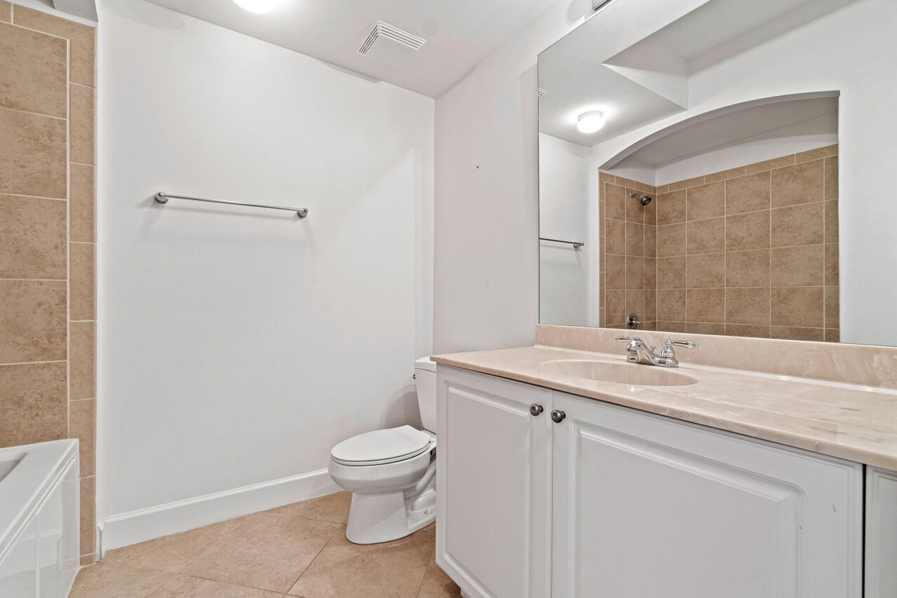 1660 Renaissance Commons Boulevard, Unit 2524 Boynton Beach, FL 33426 - Photo 24 of 27 a bathroom with a granite countertop sink a toilet and a mirror