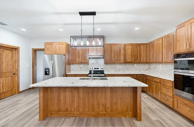 a kitchen with kitchen island granite countertop wooden floors and stainless steel appliances