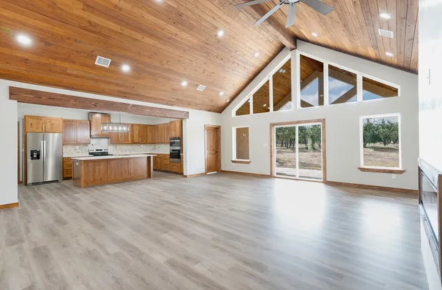 a view of an empty room with window and wooden floor
