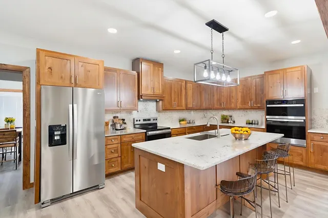 a kitchen with a stove a refrigerator and a wooden cabinets