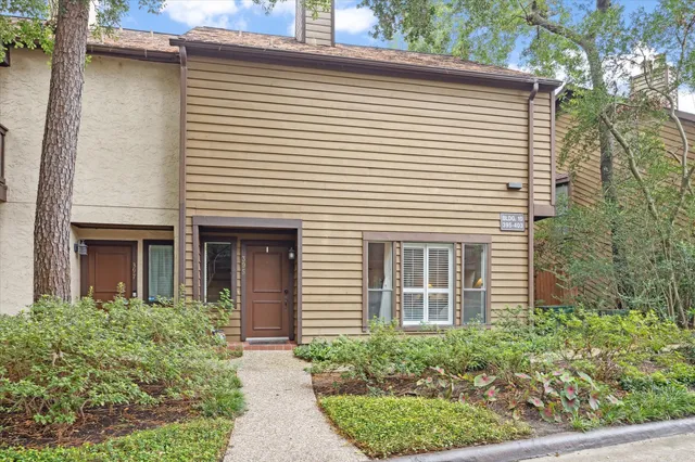 a view of a white house with a small yard and plants