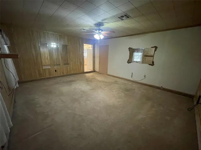 an empty room with chandelier fan and windows
