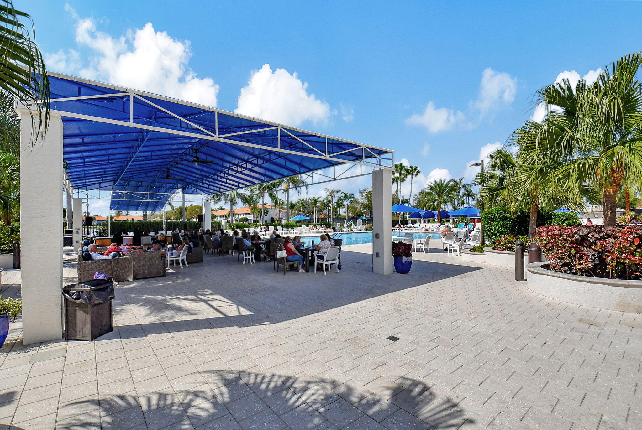 7669 Springwater Place, Unit 102 Boynton Beach, FL 33437 - Photo 111 of 116 a view of a patio with a table and chairs under an umbrella
