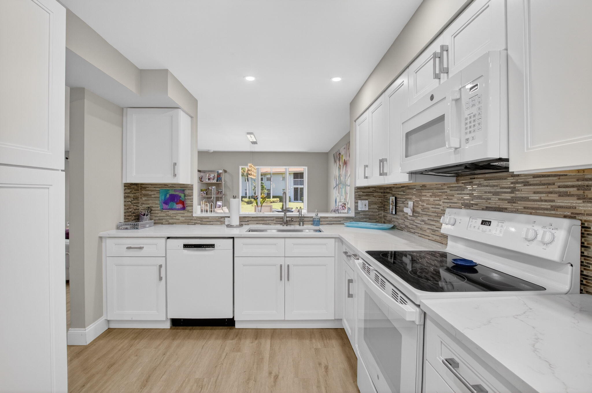 7669 Springwater Place, Unit 102 Boynton Beach, FL 33437 - Photo 20 of 116 a kitchen with granite countertop white cabinets and white appliances