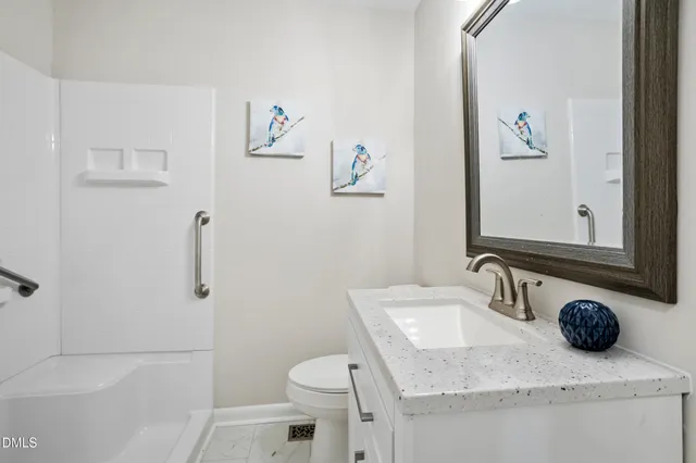 a bathroom with a granite countertop sink a toilet and a mirror