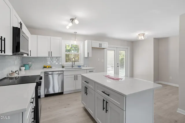 a kitchen with white cabinets and sink