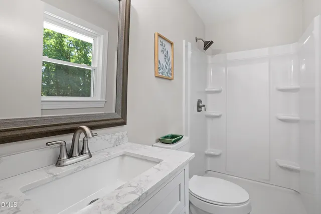 a bathroom with a granite countertop sink a toilet and shower