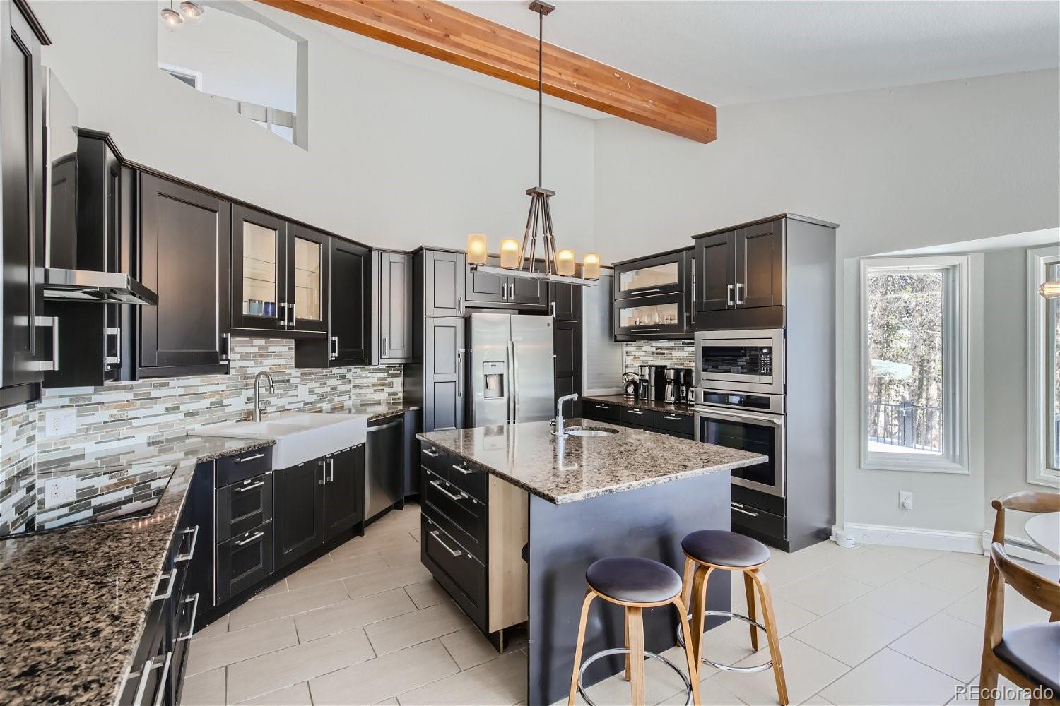 27732 Squaw Pass Road Evergreen, CO 80439 - Photo 5 of 33 a kitchen with stainless steel appliances kitchen island granite countertop a stove refrigerator and cabinets
