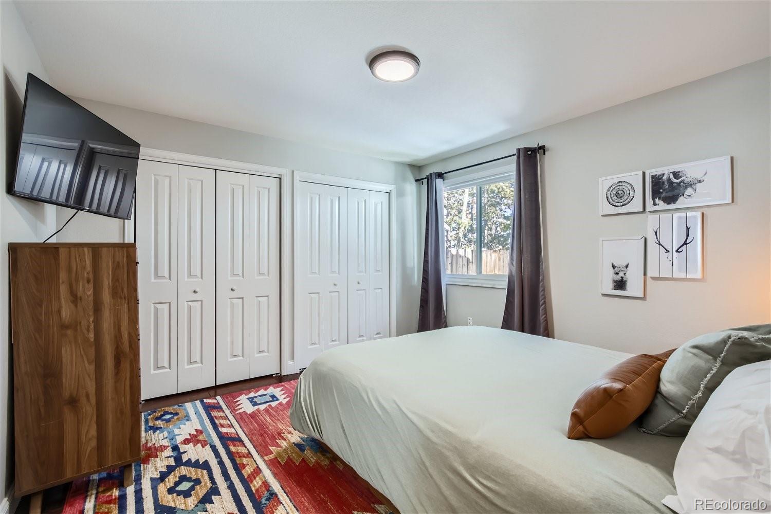 27732 Squaw Pass Road Evergreen, CO 80439 - Photo 9 of 33 a bedroom with a bed and a lamp on dresser