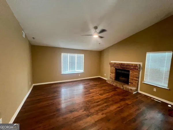 an empty room with windows fireplace and wooden floor