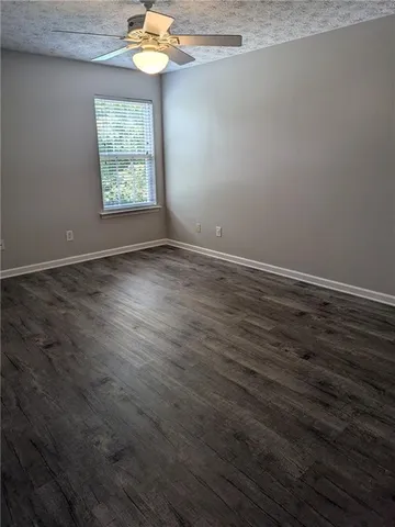 a view of an empty room with window and wooden floor