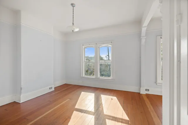 a view of an empty room with a window and wooden floor