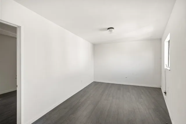 an empty room with wooden floor and window